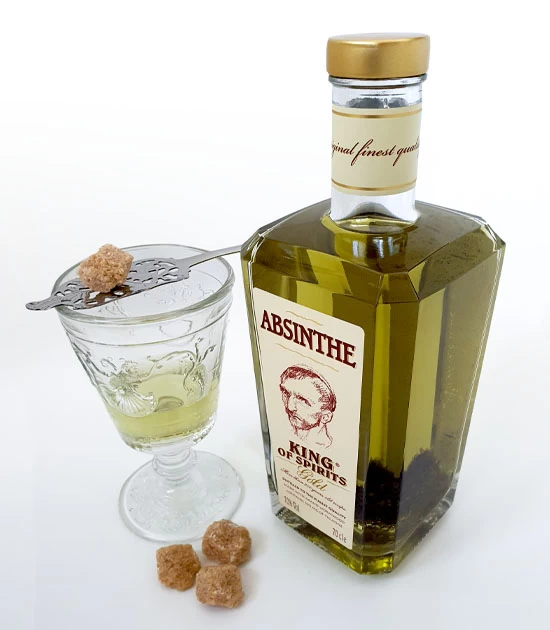 Bottle of King Gold Absinthe with absinthe drink, Versailles absinthe glass, silver spoon and sugar.