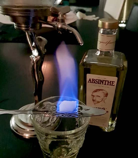 Absinthe fountain, bottle of King Gold, flaming sugar on a spoon.