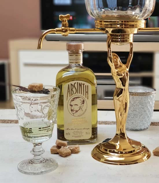 Golden absinthe fountain, glass of absinthe with spoon, and old bottle of King Gold Absinthe.