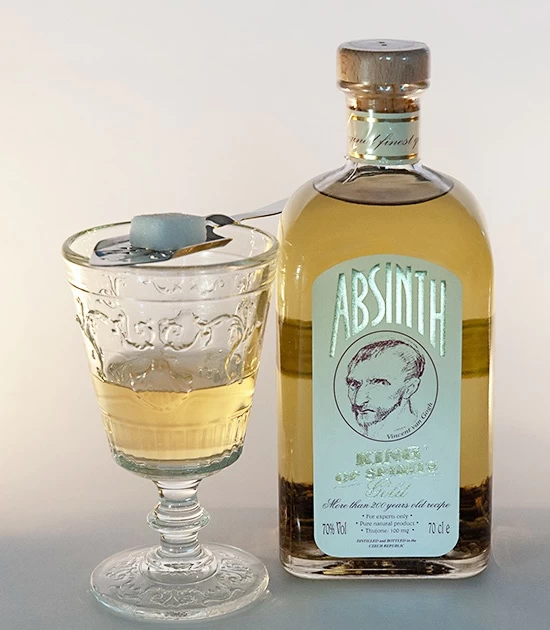 Absinthe spoon with sugar and old bottle of wormwood absinthe King of Spirits Gold.